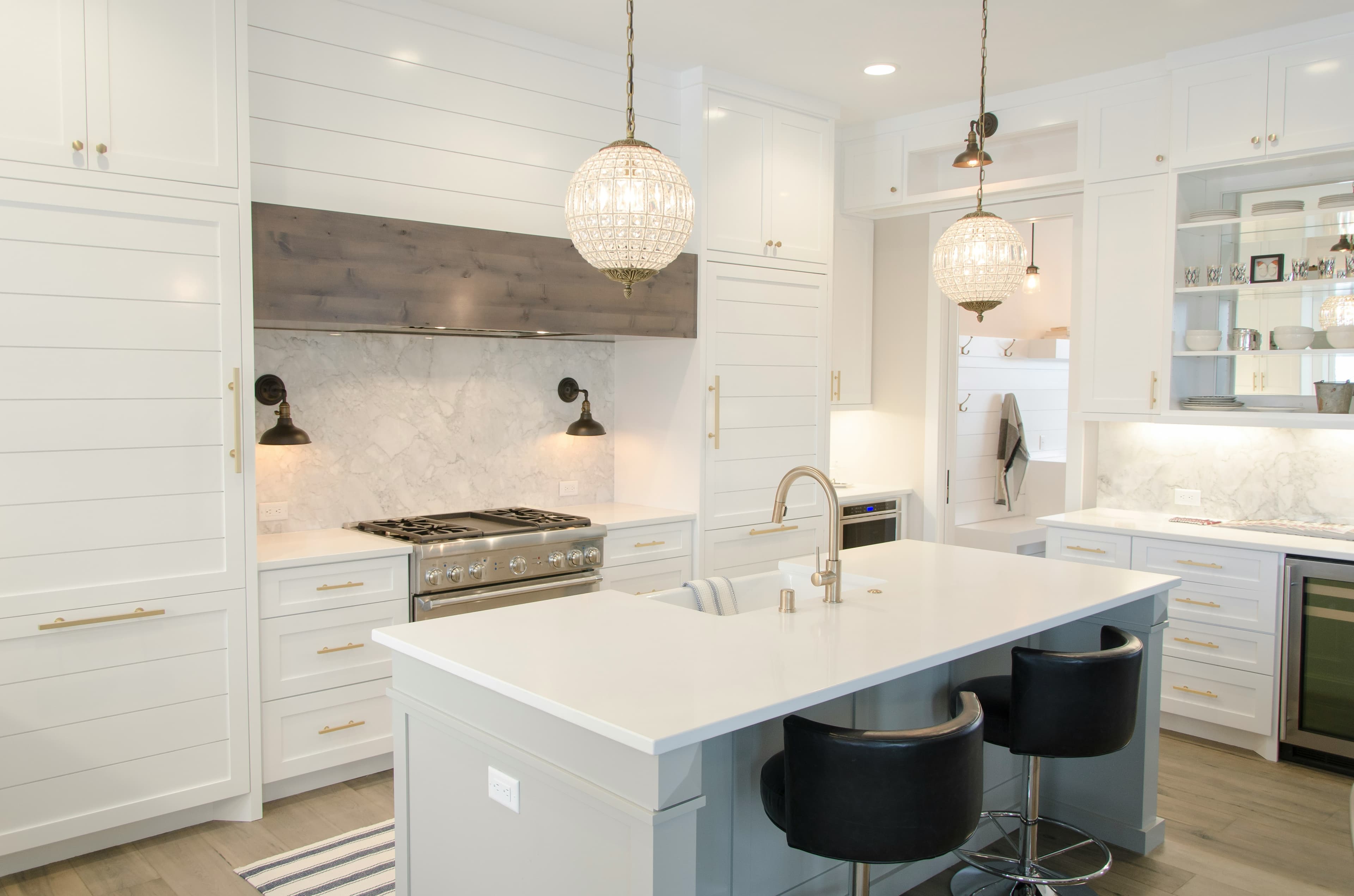 Bright kitchen with a large island, pendant lights, and brass hardware